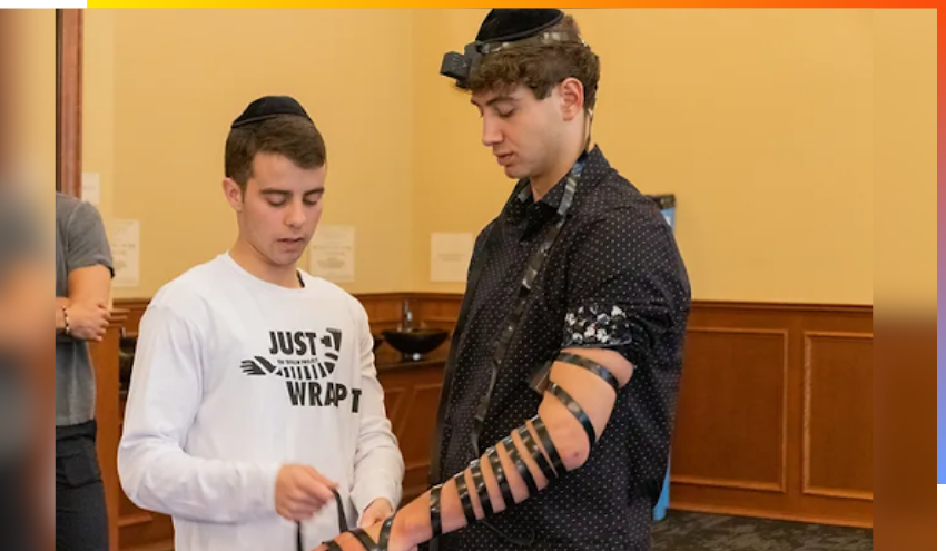 Jared Stern helping a student in Binghamton University put on Tefillin.