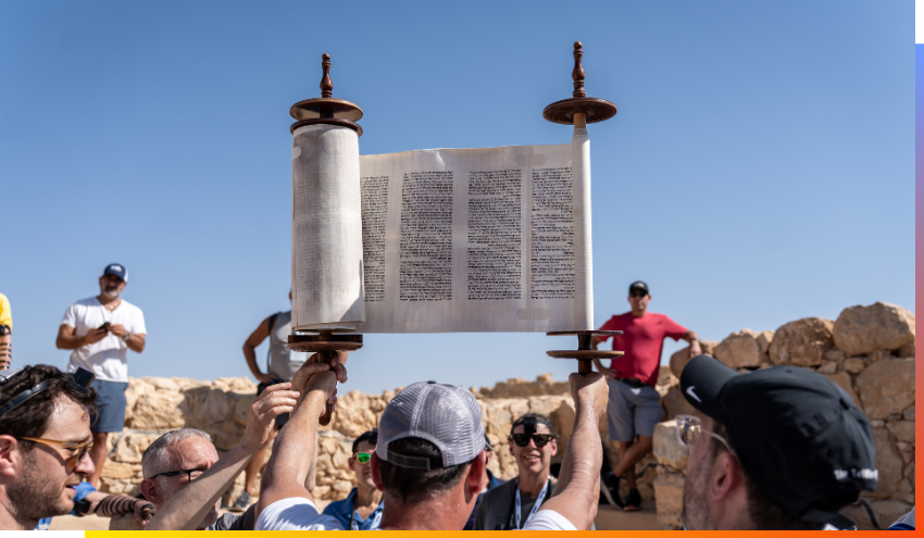 A participant of the Aish Discovery Men’s trip this past October holds up a Torah on top of Massada during morning prayers.