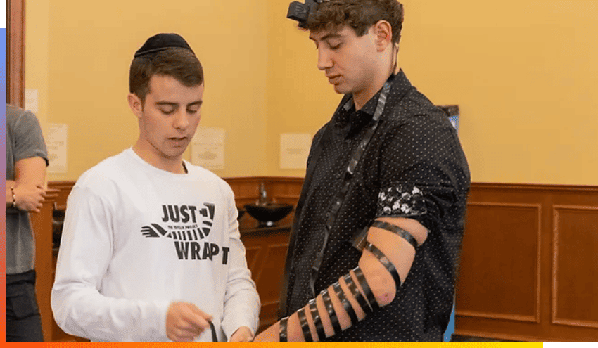 Jared wrapping Tefillin on a fellow Jew as part of the Tefillin Project that he founded